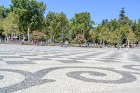 a walkway has black and white patterns on it in a park with trees in the background