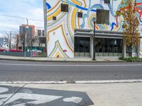 a skate board is parked on the curb of the street next to the building with the door painted in the colors of waves