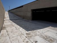 the sidewalk in front of a parking garage area is lined with concrete pavers and has a car door open on either side