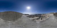 a view from a large fish eye lens of a person skateboarding along a stone pathway