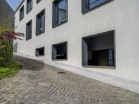 the exterior of a white building with lots of windows and potted plants on either side