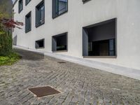 the exterior of a white building with lots of windows and potted plants on either side