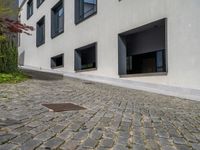 the exterior of a white building with lots of windows and potted plants on either side