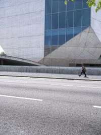 a man standing on the side of a road on his skateboard as he passes by an art building
