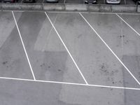 a person on a tennis racket in the middle of an empty parking lot with white lines in the floor