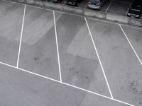 a person on a tennis racket in the middle of an empty parking lot with white lines in the floor