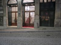 a couple of black doors sitting in the middle of a street by a building with red carpet