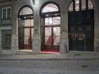 a couple of black doors sitting in the middle of a street by a building with red carpet