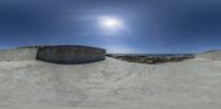 a skateboarder grinding a ramp next to the ocean on the beach and the moon