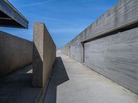 a concrete wall and walkway next to an overpass and blue sky in an empty city