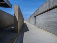 a concrete wall and walkway next to an overpass and blue sky in an empty city