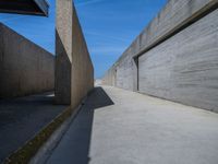 a concrete wall and walkway next to an overpass and blue sky in an empty city