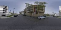 a street with a white car and multiple tall buildings in the background that are very reflective