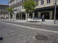 there is a building with several shops and people walking by it along the street in front of them