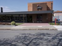 a restaurant sits empty, on a street corner in the middle of town in summer