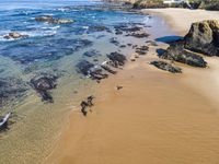 a sandy beach with waves on a sunny day near the ocean and rocks in the distance