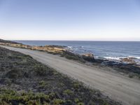 the dirt road is empty on the ocean beach side road that takes up to the rocky shore