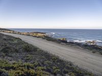 the dirt road is empty on the ocean beach side road that takes up to the rocky shore