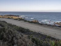 the dirt road is empty on the ocean beach side road that takes up to the rocky shore