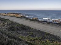 the dirt road is empty on the ocean beach side road that takes up to the rocky shore