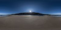 an island sits on the sand at the bottom of a beach as a sunny and clear blue sky hangs above it