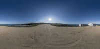 360 - angle view of a dirt road near a beach with a building and water in the background