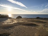 this is a sunset over the ocean near some rocks and sand area at the shoreline