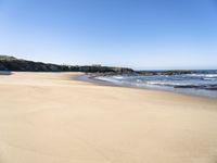 the sand is smooth and clean on the beach under a clear blue sky, in the foreground is mountains