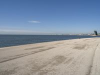 a person sitting on the beach in front of the ocean, looking at the water