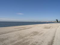 a person sitting on the beach in front of the ocean, looking at the water