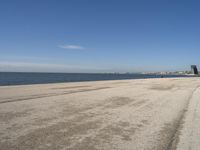 a person sitting on the beach in front of the ocean, looking at the water