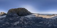 a 360 - view shot of rocks by the beach and a seagull in the sky