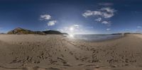 a camera lens view of a beach and sky with tracks in the sand in front of the beach