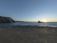 sunset view of rock formations with beach and ocean in background at dusk with blue sky