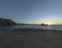 sunset view of rock formations with beach and ocean in background at dusk with blue sky