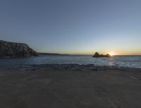 sunset view of rock formations with beach and ocean in background at dusk with blue sky