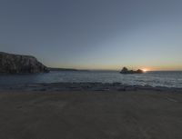 sunset view of rock formations with beach and ocean in background at dusk with blue sky