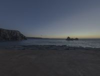 sunset view of rock formations with beach and ocean in background at dusk with blue sky