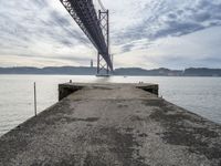 a bridge that crosses the water under a partly cloudy sky during the day with only one person