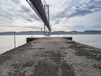 a bridge that crosses the water under a partly cloudy sky during the day with only one person