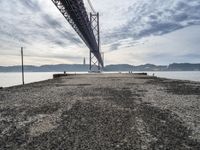 a bridge that crosses the water under a partly cloudy sky during the day with only one person