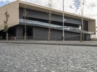 an empty parking lot with several trees next to it and the building is very large