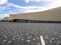 a large stone courtyard next to an empty building with a sky background on the horizon