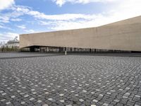 a large stone courtyard next to an empty building with a sky background on the horizon