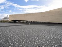 a large stone courtyard next to an empty building with a sky background on the horizon