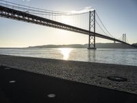 a bridge over the water in front of a sandy area with a walkway and bike path