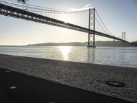 a bridge over the water in front of a sandy area with a walkway and bike path