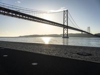 a bridge over the water in front of a sandy area with a walkway and bike path