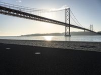 a bridge over the water in front of a sandy area with a walkway and bike path