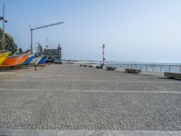 four boats are lined up outside at the beach in front of a crane and water